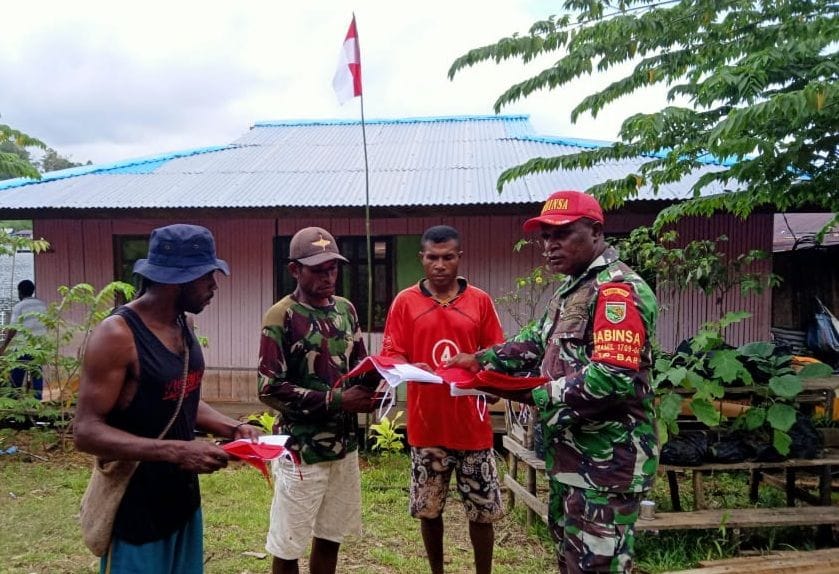 BAKTI UNTUK NEGERI, BABINSA YAPEN BARAT BAGIKAN BENDERA MERAH PUTIH KEPADA WARGA BINAANNYA