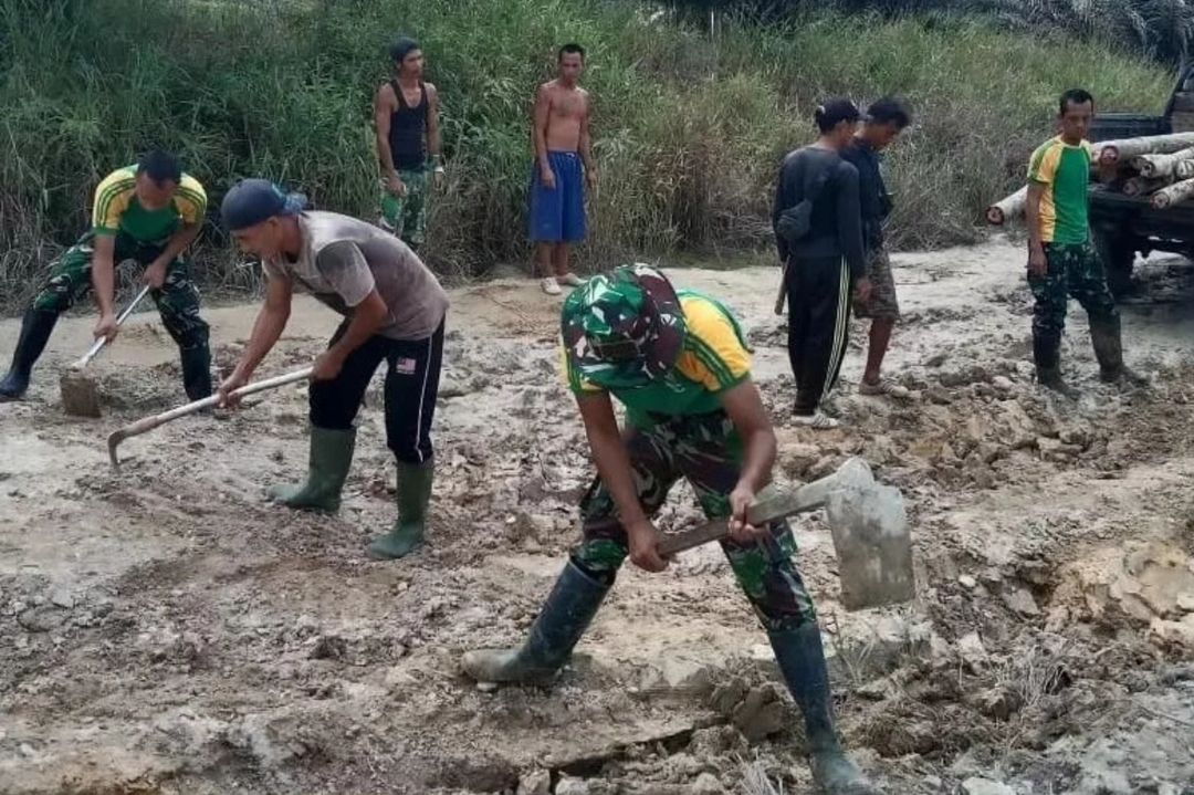 Satgas Yonarmed 10 Kostrad Bersama Warga Gotong Royong Memperbaiki Jalan Rusak