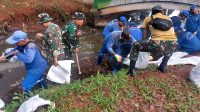 Kolaborasi Babinsa Kelurahan Lubang Buaya Bersama Petugas Dinas Tata Air Bersihkan Saluran Air